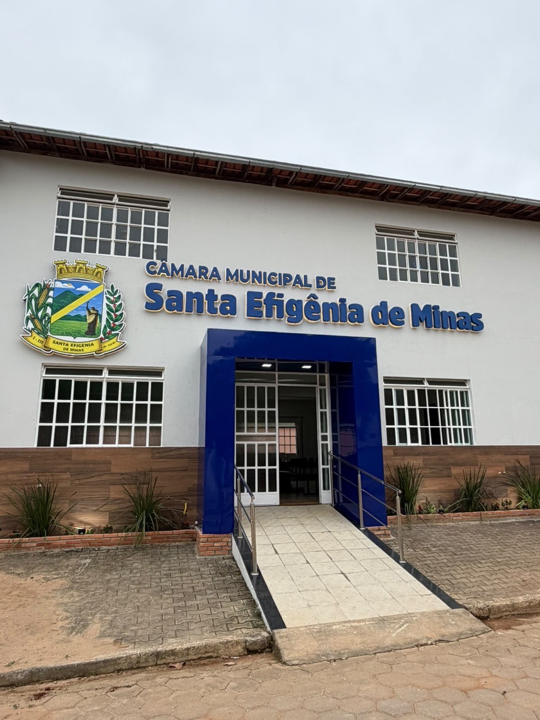 Fachada da Câmara Municipal de Santa Efigênia de Minas com letras caixa azuis, brasão e pórtico em ACM